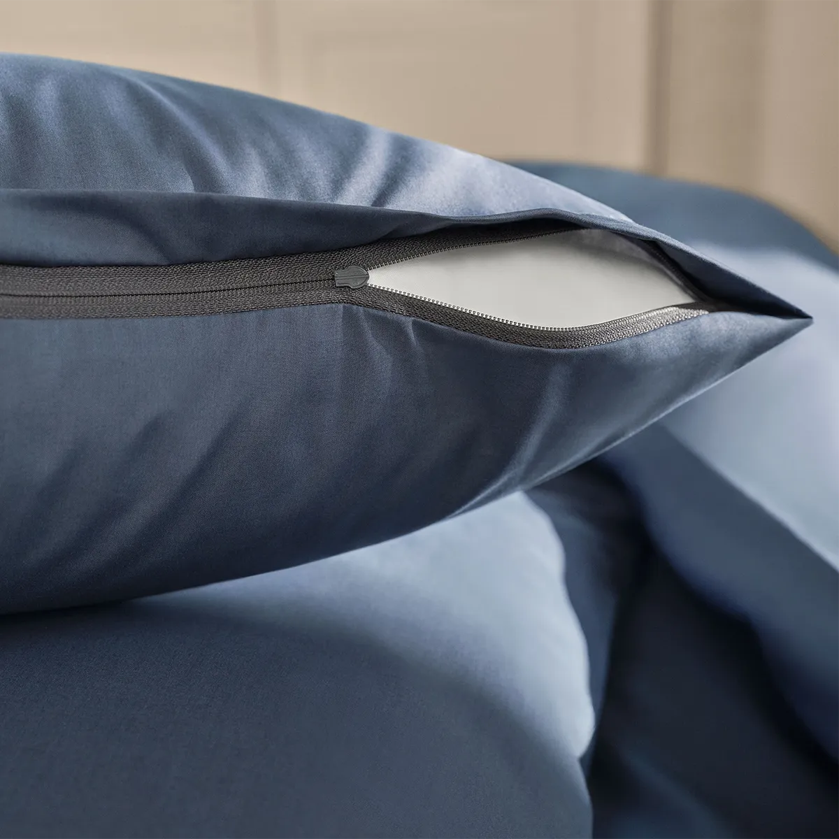 Detailaufnahme des Schlossberg Bettwäsche Ben Ink Kissenbezugs mit einem hochwertigen, verdeckten Reißverschluss. Der tiefblaue Stoff kombiniert edles Design mit praktischer Funktionalität für höchsten Schlafkomfort.