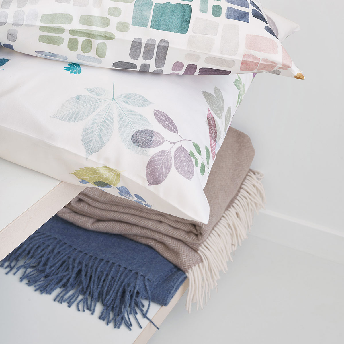 Eliv Kissen mit Blättermuster Kissen aus der Eliv Bettwäsche Kollektion mit Blättermuster in Pastellfarben, liegend auf einem Regal, dekoriert mit einer Decke.