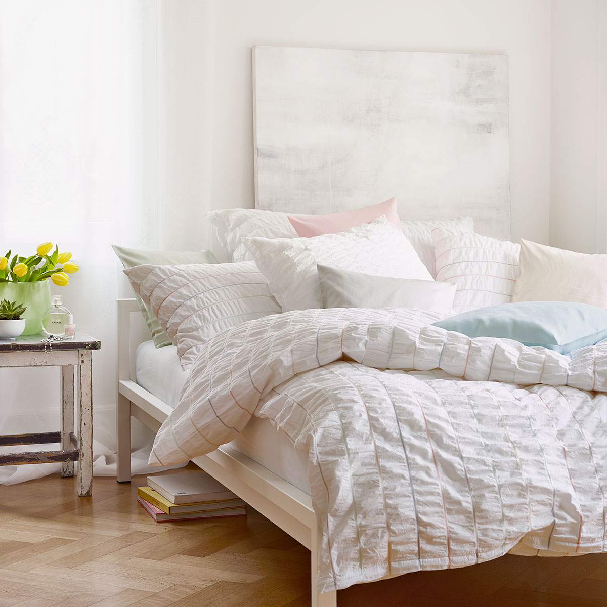 Gemütliches Schlafzimmer mit Nelson Bettwäsche Ein helles Schlafzimmer, das Bett ist mit der Nelson Bettwäsche in einem feinen Streifenmuster in Pastellfarben bezogen.