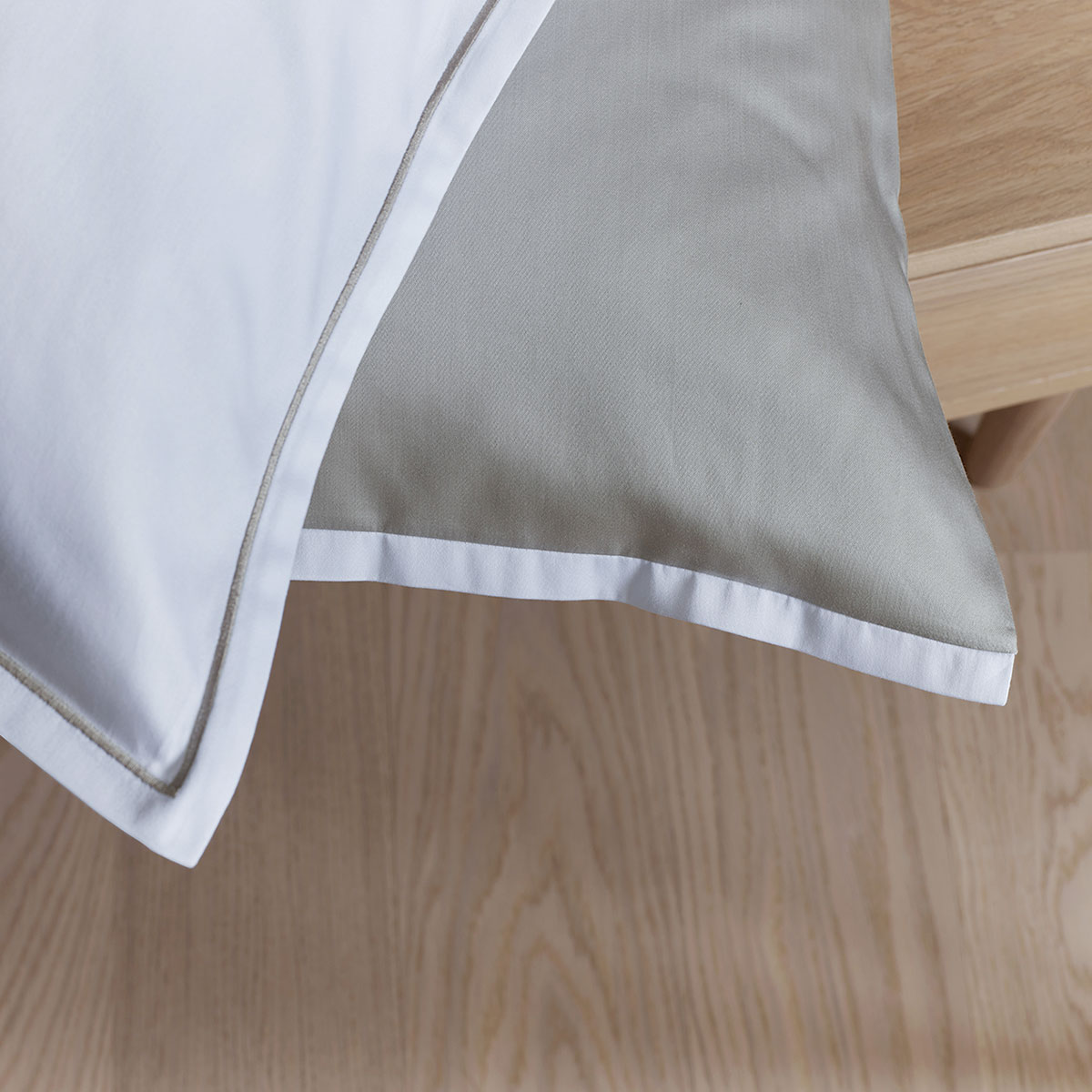 Detailaufnahme der Bettwäsche Clark in weiss und ardoise Eine Nahaufnahme der Bettwäsche Clark, die den weissen Bezug mit hellem Rand und die hochwertige Verarbeitung zeigt.