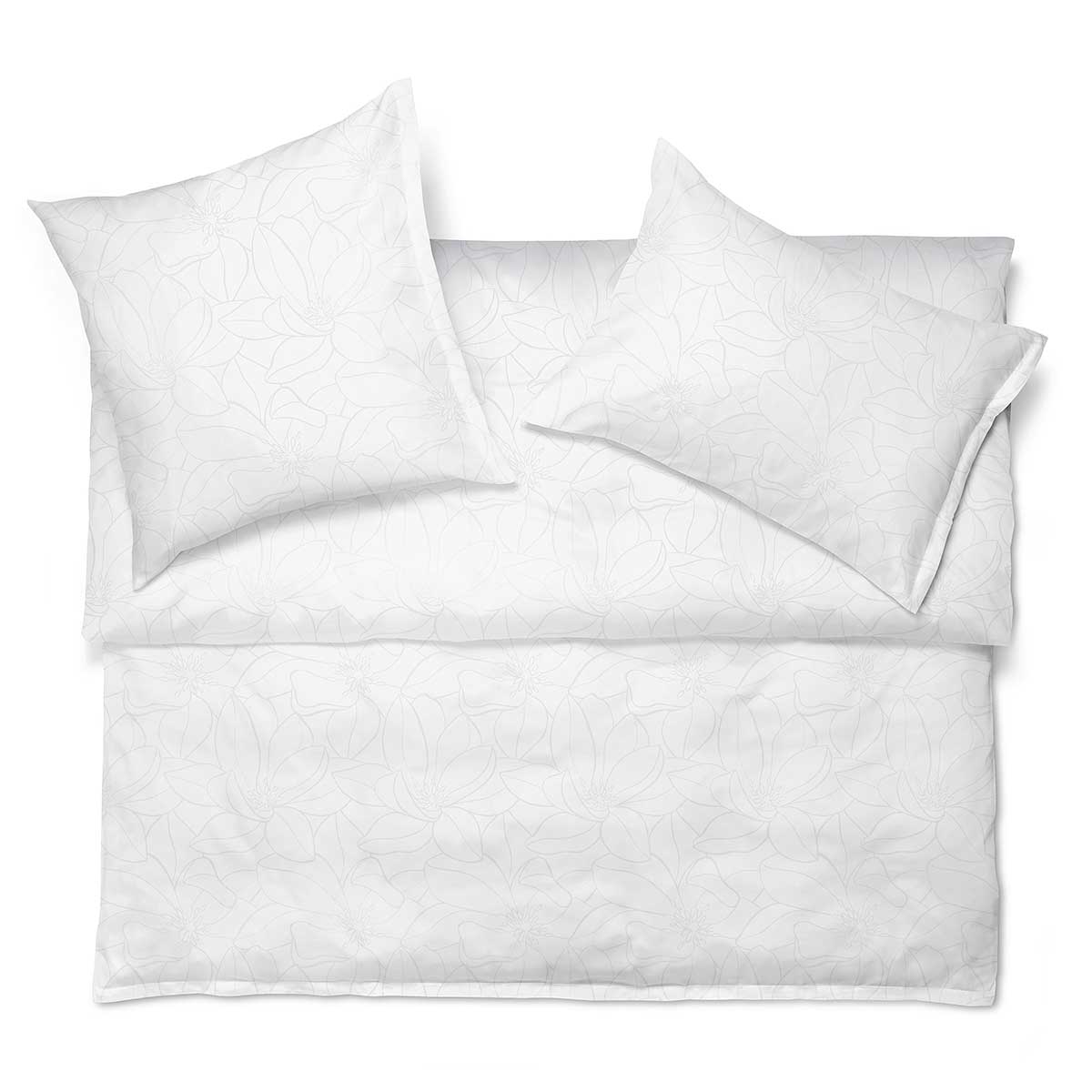 Bettwäsche Set Magnolia in Weiss mit dezentem floralem Muster, arrangiert auf einem Bett.