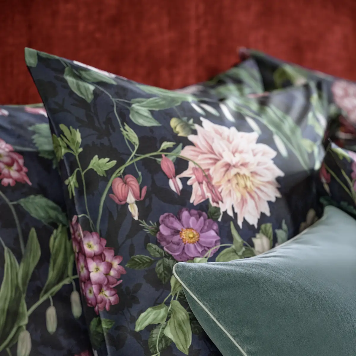Dunkelblaues Ophelia Kopfkissen Nahaufnahme eines Kopfkissens mit dem dunkelblauen floralen Muster der Ophelia Bettwäsche, ergänzt durch ein grünes Zierkissen.