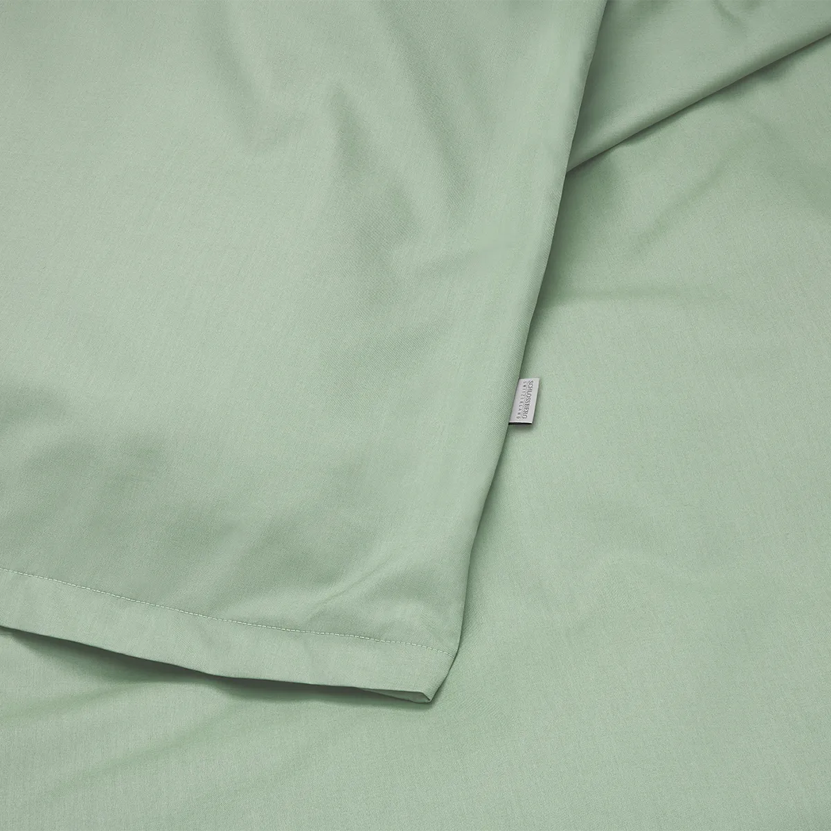 Detailaufnahme der Schlossberg Bettwäsche Ben Leaf in sanftem Grünton. Der hochwertige Stoff mit feiner Webstruktur vermittelt luxuriöse Qualität und natürliche Eleganz.