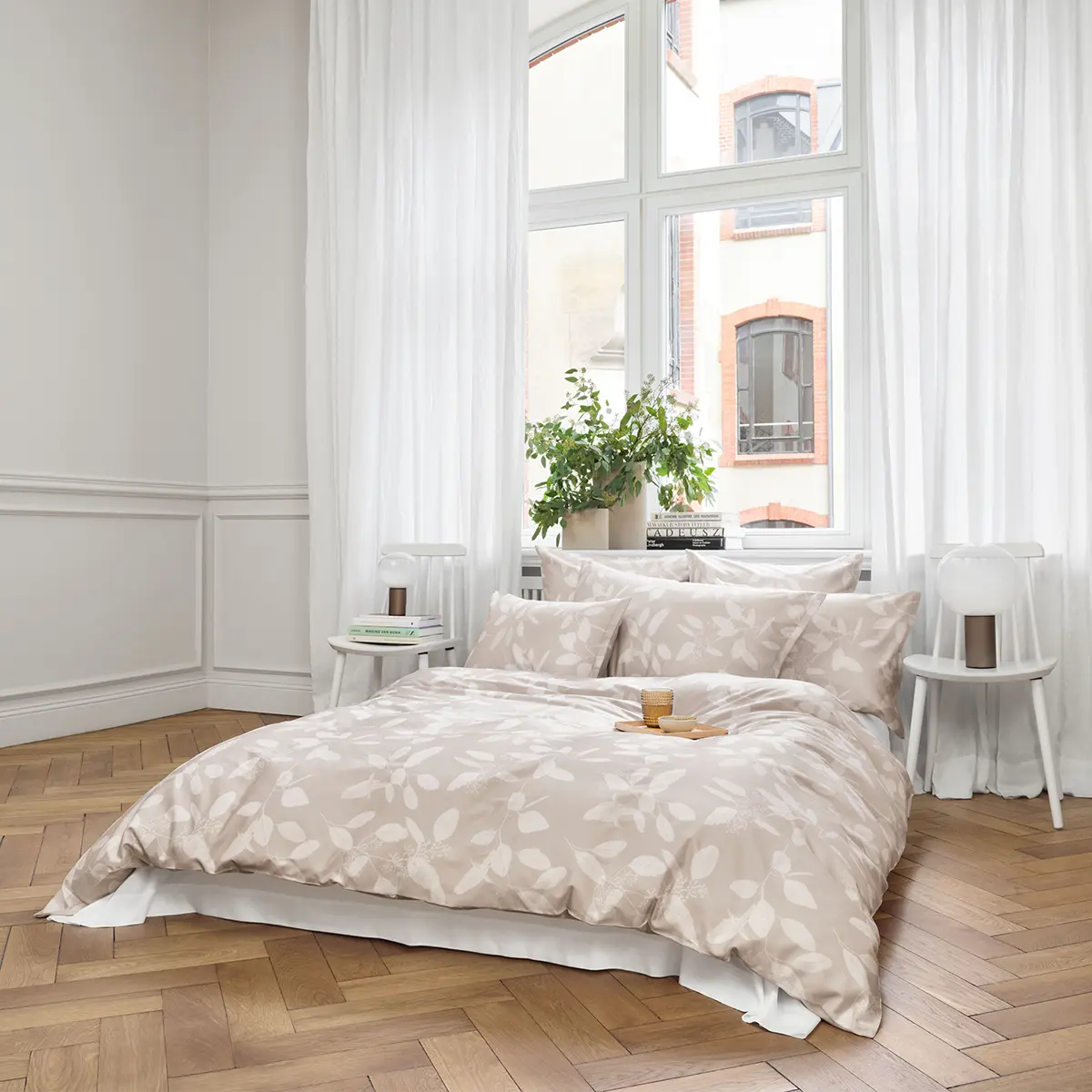 Elegant eingerichtetes Schlafzimmer mit der beigen Omeo Bettwäsche, dekoriert mit Pflanzen und modernen Möbeln.