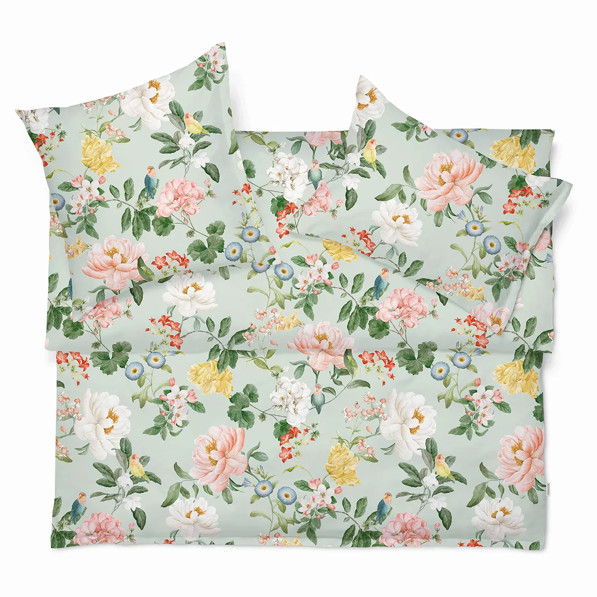 Bettwäsche Artemis mit buntem Blumenmuster und grünen Kissenbezügen, arrangiert im Freien.