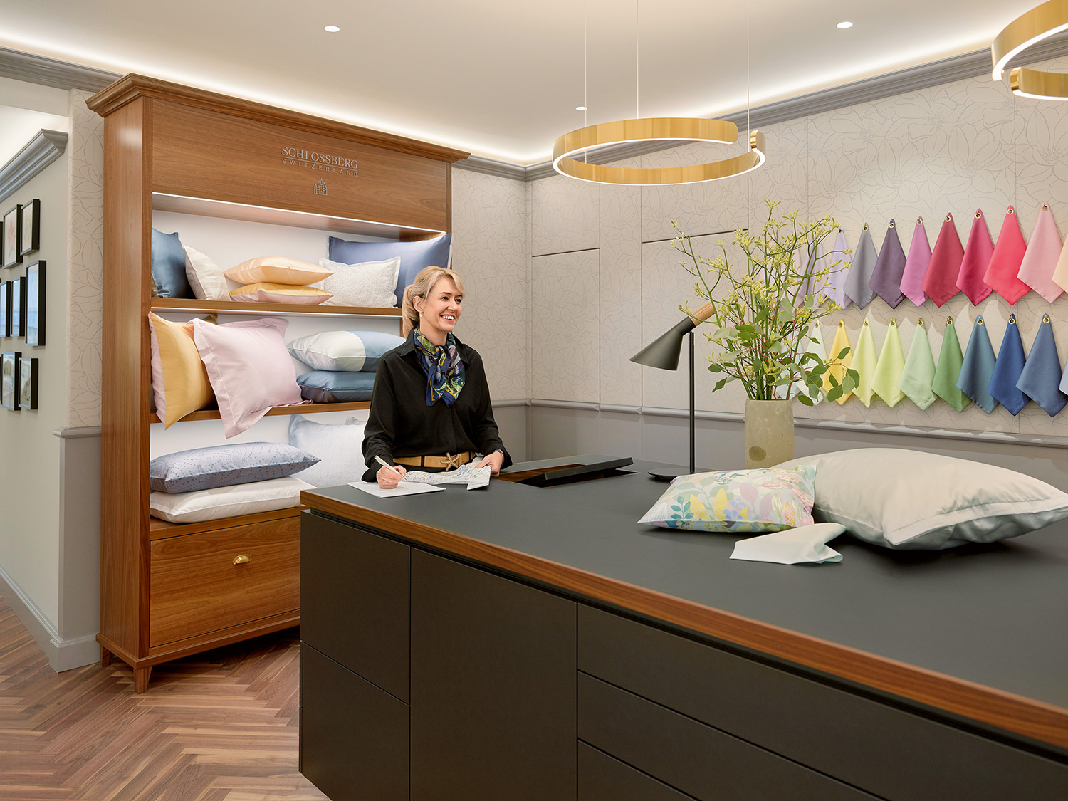 Schlossberg_Boutique_Zurich_2_1500x1125 Eine Frau steht lächelnd in der neu gestalteten Schlossberg Boutique Zürich an einem Ateliertisch.