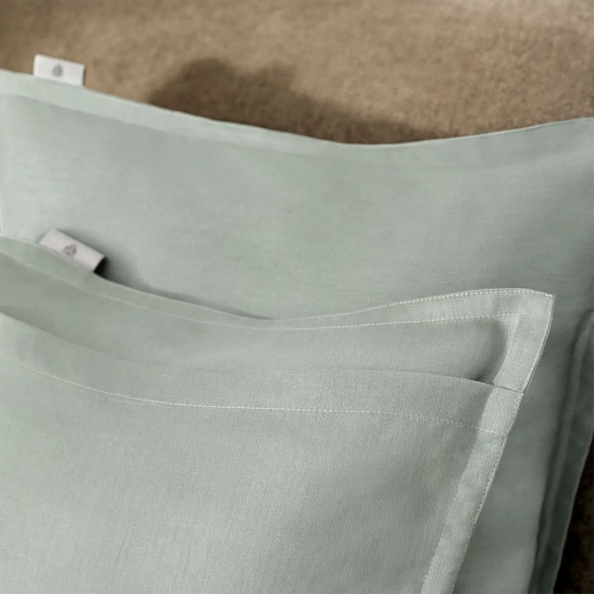 chlossberg Zierkissen Solene Sage – Detailansicht des eleganten Hotelverschlusses Nahaufnahme des Schlossberg Zierkissen Solene Sage mit hochwertigem Hotelverschluss. Der feine Stoff in sanftem Salbeigrün und die präzise Verarbeitung unterstreichen die elegante und zeitlose Qualität des Kissens.