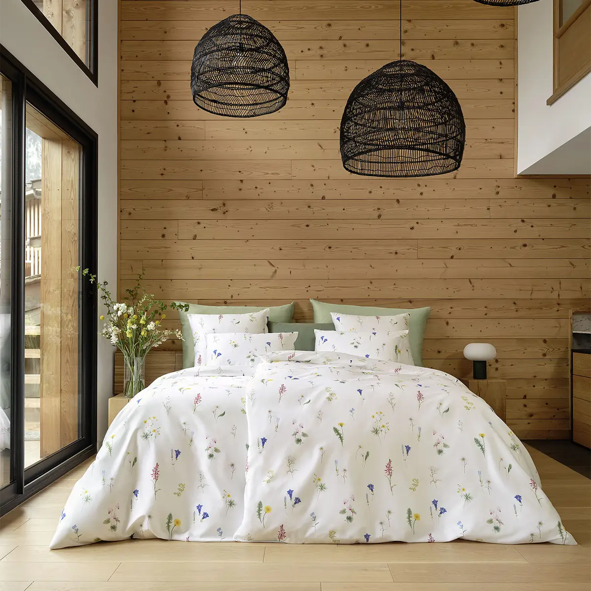 Schlafzimmer mit der Bettwäsche "Flurina" in Holzoptik Ein gemütliches Schlafzimmer mit Holzverkleidung, dekoriert mit der weissen Bettwäsche "Flurina", die mit einem zarten Blumenmuster verziert ist.