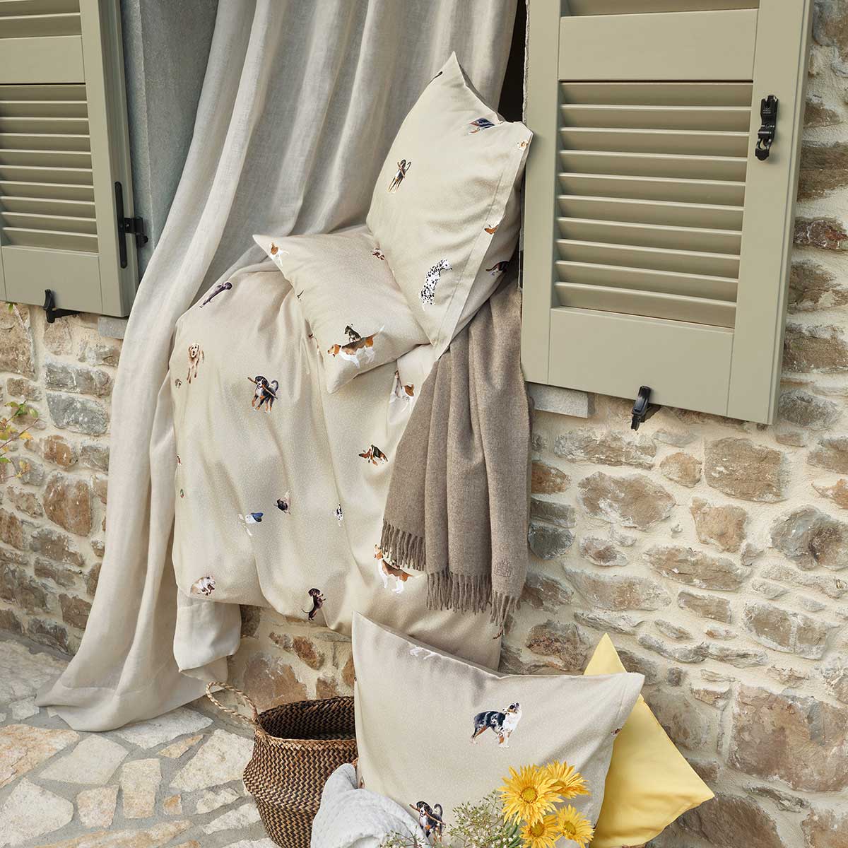 Bello Bettwäsche in einem Outdoor-Szenario, drapiert über einem Fensterbrett, umgeben von Vorhängen, Decken und Kissen.