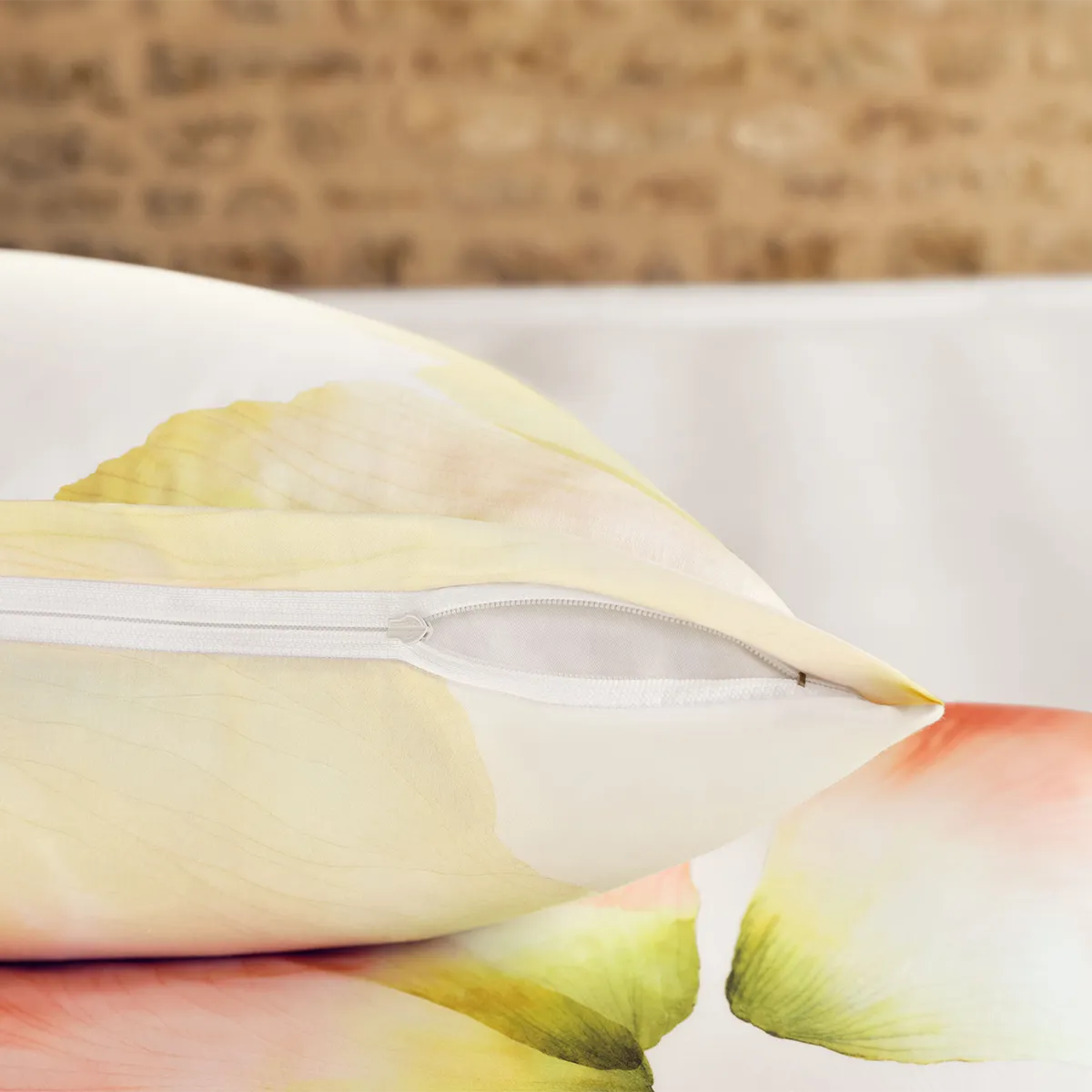 Nahaufnahme eines Schlossberg-Kissenbezugs aus der Aurora-Kollektion mit floralem Blütenmuster in sanften Gelb- und Orangetönen. Der verdeckte Reißverschluss sorgt für eine elegante und nahtlose Optik.