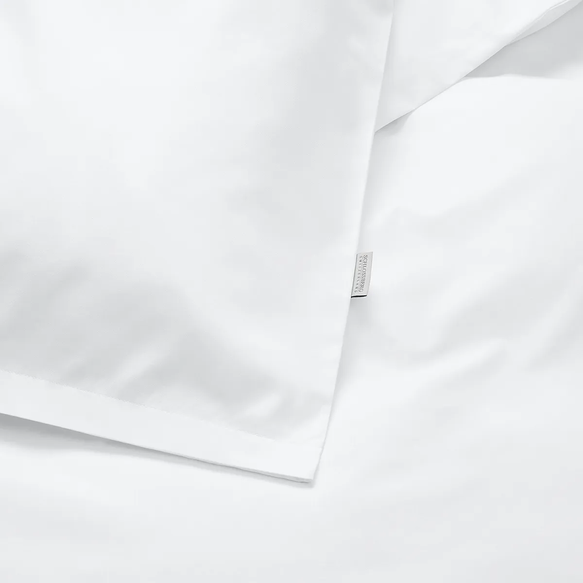 Schlossberg Bettwäsche Ben White – Closeup Nahaufnahme der Schlossberg Bettwäsche Ben in der Farbe White. Die hochwertige, schlichte weiße Bettwäsche überzeugt durch feine Verarbeitung, weichen Stoff und eine edle Optik, die für eine zeitlose und elegante Schlafumgebung sorgt.