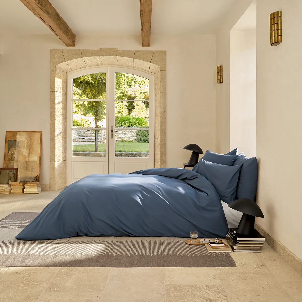 Ein luxuriös eingerichtetes Schlafzimmer mit der Schlossberg Bettwäsche Ben Ink in einem tiefen Blauton. Die hochwertige Bettwäsche sorgt für eine elegante und beruhigende Atmosphäre, perfekt kombiniert mit modernen Designelementen und natürlichem Licht.