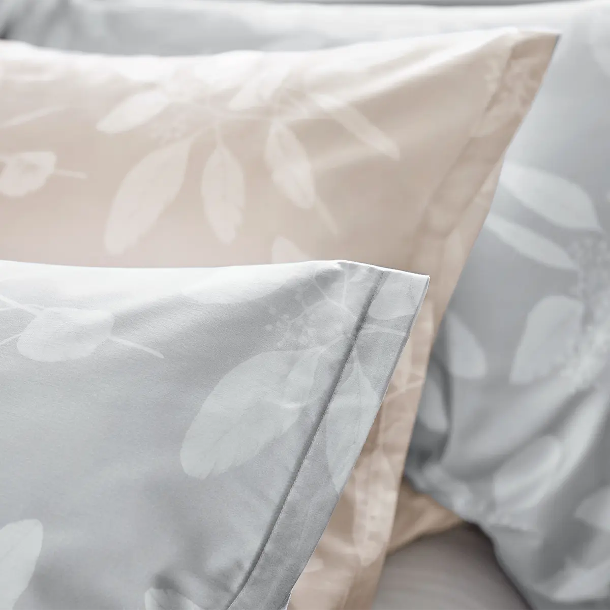 Detailansicht der Omeo Kissen Nahaufnahme von Kissen mit der Omeo Bettwäsche in beige und grau, die ein dezentes Blätterdesign zeigen.