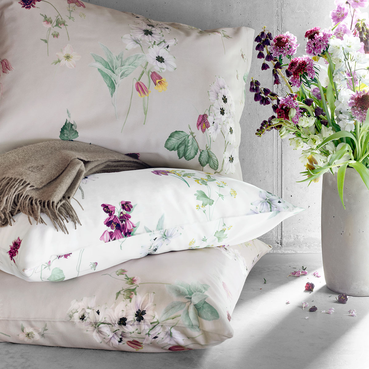 Dekorative Bettwäsche "Freya" mit floralen Akzenten Nahaufnahme von dekorativen Kissen und Bettwäsche "Freya" mit floralen Akzenten, kombiniert mit einem Blumenstrauss in einem modernen Schlafzimmer.
