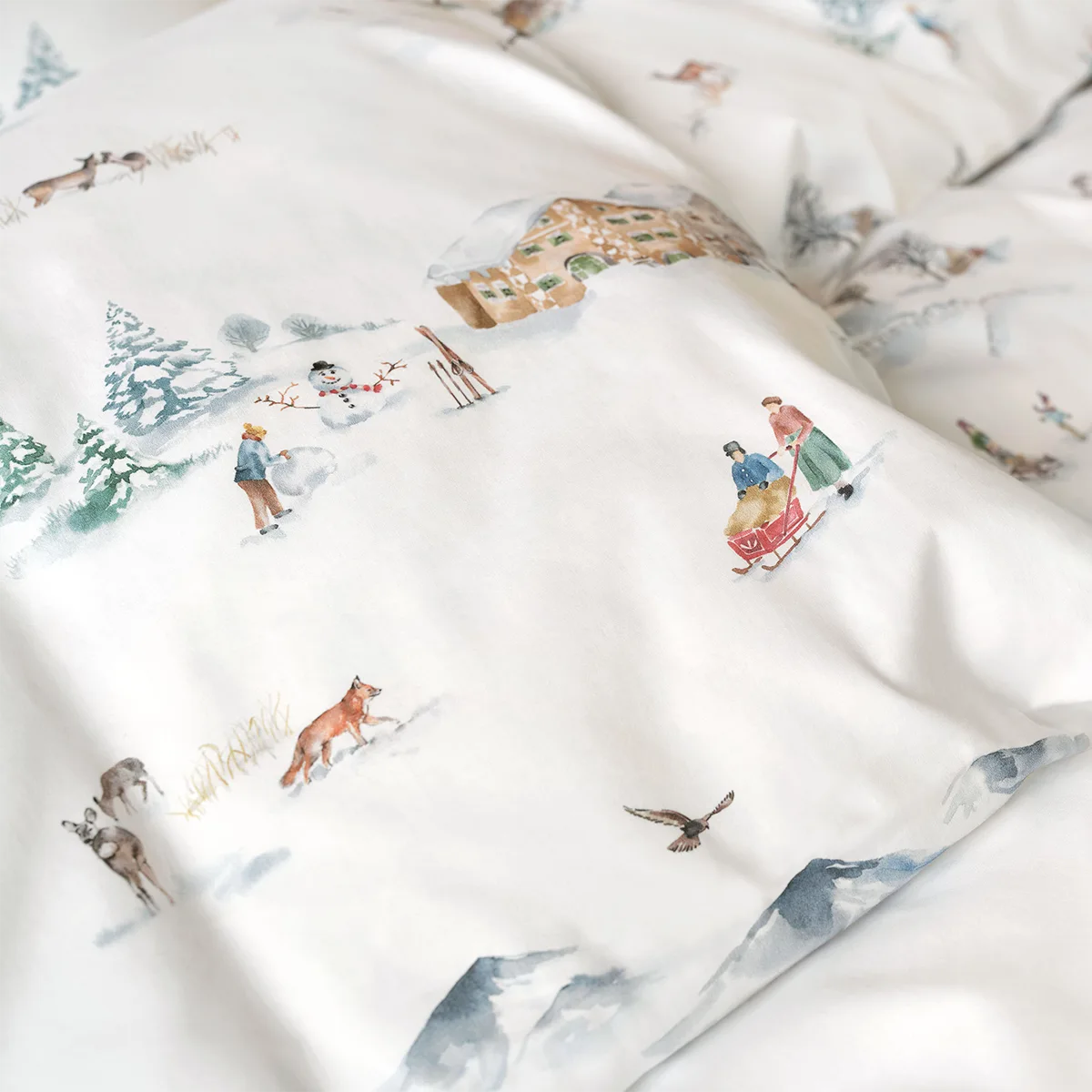 Nahaufnahme der Montagne Bettwäsche mit einem winterlichen Bergmotiv, inklusive Schneemann, Schlitten und Tieren.
