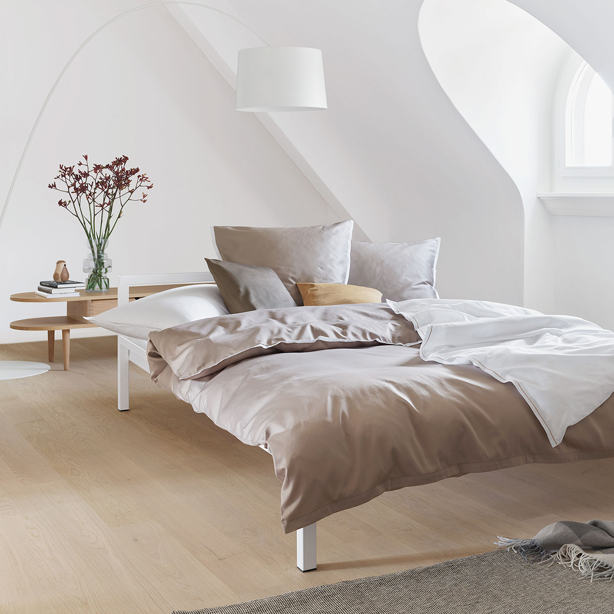 Stilvolles Schlafzimmer mit Bettwäsche Clark in taupe und weiss Ein stilvolles Schlafzimmer mit einem Bett, das mit der sablefarbenen und weissen Bettwäsche Clark bezogen ist. Dezente Dekorationen und modernes Design runden das Bild ab.