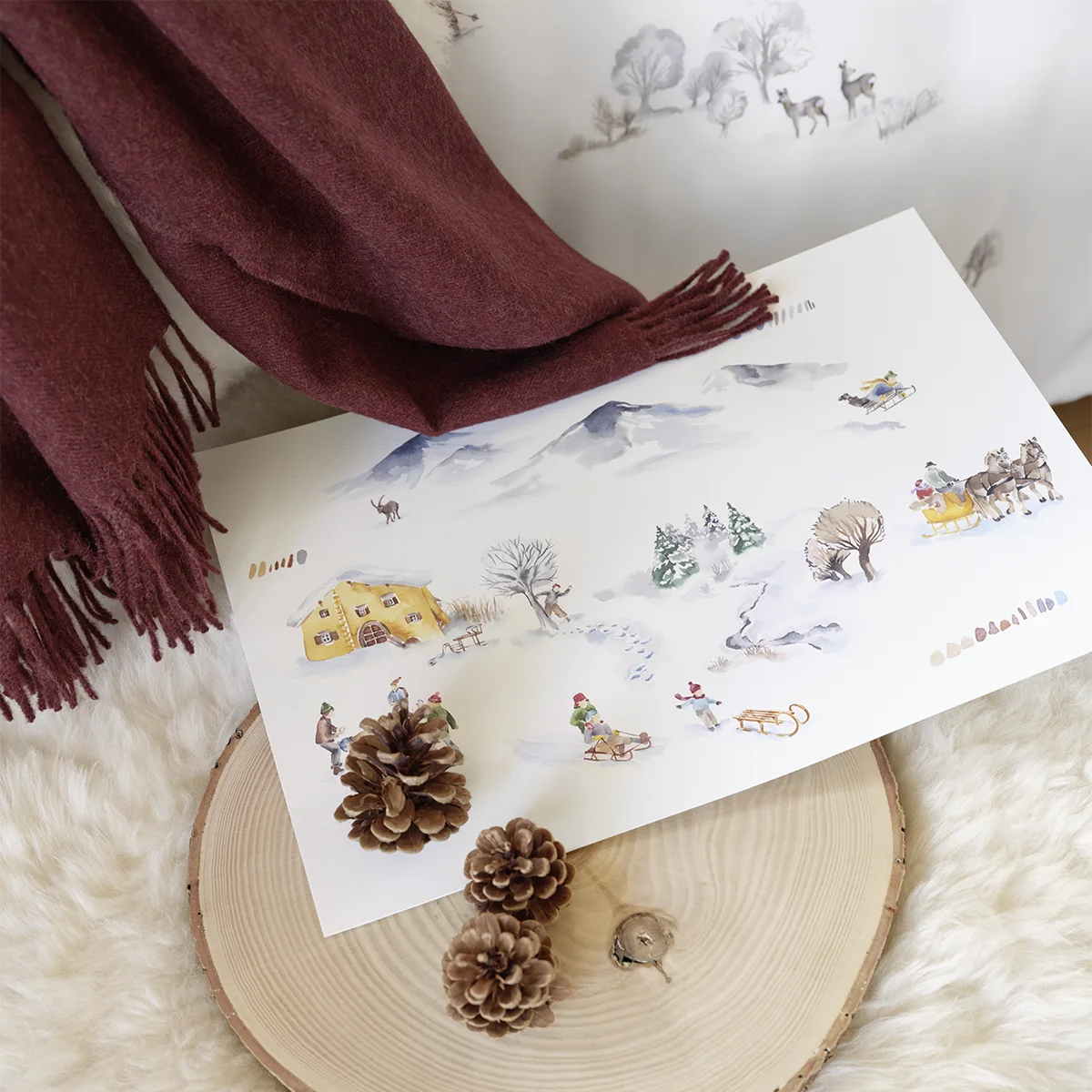 Nahaufnahme der Montagne Bettwäsche mit einem Alpenmotiv, dekoriert mit einem Pinienzapfen und einem braunen Schal.