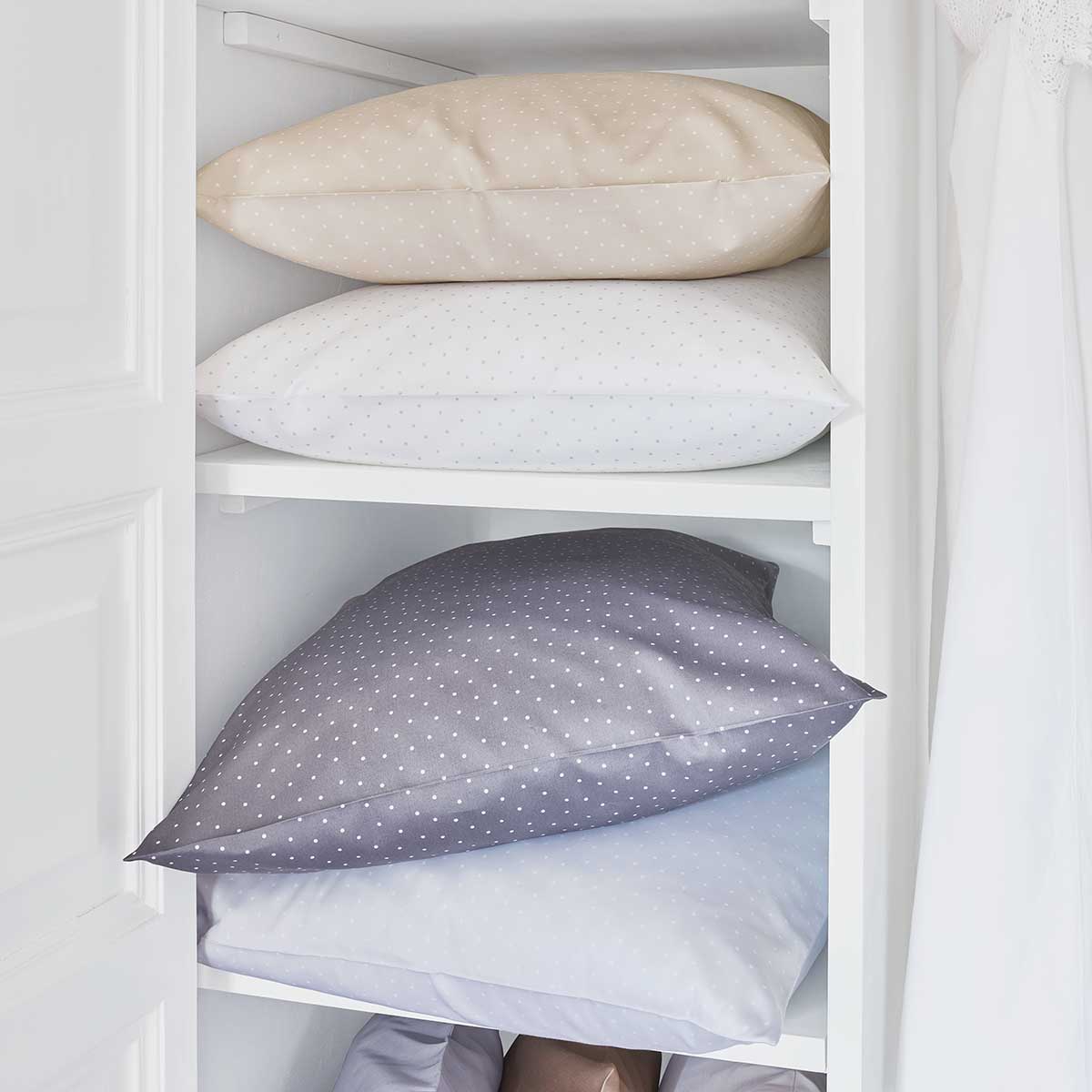 Gestapelte Kissen der Bettwäsche Emily Gestapelte Kissen der Bettwäsche Emily in verschiedenen Farben (Beige, Weiss, Grau) in einem Regal.